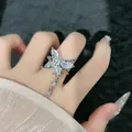 Close-up detail of a silver butterfly ring with sparkling crystal tassels on a woman's hand. - Style 2 Adjustable Ring