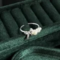 Detailed view of an elegant silver bow ring with pearls on a green velvet jewelry stand - No.4 Open Ring (Triple Pearl Bowknot Style)