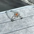 Detailed macro shot of an elegant silver flower open ring with a vibrant orange garnet stone - Streamlined Flower Style (No. 22) / Garnet Red