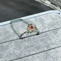 Detailed macro view of a silver flower-shaped open ring with red garnet center stone. - 3D Petal Design (No. 27) / Garnet Red