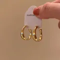 Close-up of chunky gold hoop earrings featuring a shiny finish and S925 silver mark on the tag - Stud Style (X1929 Gold) / A2085 Gold / Gold