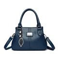 Elegant navy blue leather handbag featuring decorative leaf and pearl bag charms - Blue