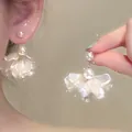 Close-up detail of elegant French style white petal pearl earrings worn on an ear - Translucent Petal Pearl Style (A2526 Gold)