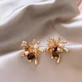 Close-up of gold fireworks stud earrings with brown and white beads on satin - Maillard Style Fireworks Shaped Studs (E6798)