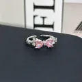 Primer plano de un anillo de lazo con gemas rosas en forma de corazón y acabado plateado. - Anillo ajustable estilo 3