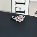 Primer plano detallado de un elegante anillo de plata con piedra de corazón rosa y perlas - Anillo ajustable estilo 4