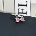 Primer plano de un anillo de lazo plateado con piedras de corazón rosa y circonio. - Anillo ajustable estilo 5