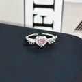 Detalle macro de un anillo romántico plateado con corazón rosa y alas laterales - Anillo ajustable estilo 6