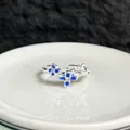 Vista detallada de un anillo abierto plateado con elegantes flores de esmalte azul - Anillo ajustable estilo 2