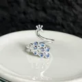 Vista de detalle de un anillo de pavo real plateado con plumas en esmalte azulado. - Anillo ajustable estilo 4