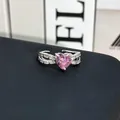 Vista macro de un anillo con gema rosa en forma de corazón y piedras laterales brillantes. - Anillo Abierto N.º 18