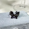 Primer plano de un anillo de mariposa negro gótico con piedras preciosas púrpuras. - Estilo Mariposa Púrpura