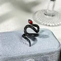 Primer plano detallado de un anillo de serpiente negro gótico con un ojo de gema roja - Estilo serpiente negra con ojos rojos