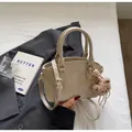 Vue détaillée d'un sac à main beige texture crocodile avec charme d'ours en peluche - Ours / Kaki