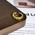 Makrodetail eines vergoldeten Rings mit funkelnden gelben Kristallen auf Holzgrund - Stil 1 Offener Ring (32022154)