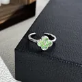 Makroansicht eines funkelnden mintgrünen Kleeblattrings auf einem schwarzen Lederdisplay. - Nr. 2 Kleeblatt Minzgrün Zirkonia Offener Ring
