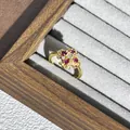 Nahaufnahme eines goldenen Blumenrings mit roten Steinen in einer Samtschachtel - Stil 1 Verstellbarer Ring (Blume/Unregelmäßig)