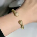 Vista dettagliata del bracciale rigido aperto in cavo d'oro intrecciato con cristalli - Hemispherical bracelet