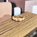 Detalle macro de un anillo abierto dorado con un patrón de flores de esmalte rosa vintage - Anillo ajustable estilo 3