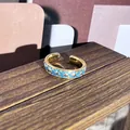 Vista detallada de un anillo retro dorado con patrones florales de esmalte azul - Anillo ajustable estilo 7