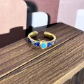 Vista de primer plano de un anillo vintage dorado con esmalte azul y piedra azul claro. - Anillo ajustable estilo 9