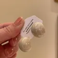 Nahaufnahme eleganter beiger runder Ohrklemmen ohne Ohrloch auf Schmuckkarte - Unregelmäßige Geometrische Ohrknochen Clip Stil (A2372) / Cremeweiß