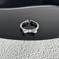 Elegant silver bow ring with sparkling cubic zirconia set on a black reflective surface - Style 1