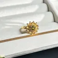 Detailaufnahme eines goldenen Sonnenblumenrings mit funkelndem grünem Edelsteinzentrum - Sonnenblume Smaragd Edelstein Stil (Nr.8)