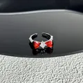Macro detail of a silver-toned open ring featuring a vibrant red bow and a clear crystal - Style 7