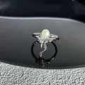Gros plan détaillé d'une bague à nœud argentée ornée d'une perle blanche centrale - Style 15