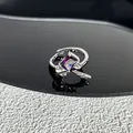 Gros plan d'une bague nœud argentée ornée d'une magnifique pierre rectangulaire violette. - Style 16