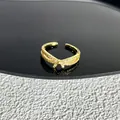 Vue détaillée d'une bague nœud dorée avec pierres scintillantes sur fond texturé contrasté - Style 17