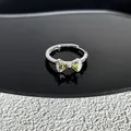 Vue détaillée d'une bague nœud en argent ornée de pierres précieuses vert clair éclatantes - Style 27
