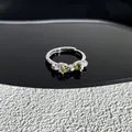 Gros plan détaillé d'une bague nœud élégante avec des pierres vert olive en cœur - Style 29