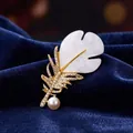 Elegant gold feather brooch with sparkling crystals and pearl on blue velvet background - White Acetate Mother-of-Pearl Rainbow Rhinestone Pearl Root Feather Style (XD824348)