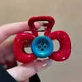 Close-up view of a vibrant red bow-shaped hair claw clip featuring a unique blue button center - Ancora Red Bow Button Style (F1433)