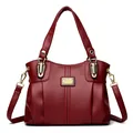 Elegante bolso de mano en cuero granulado rojo oscuro con detalles dorados y correa. - Rojo