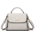 Elegant light grey pebble grain leather handbag with a gold kangaroo logo accent - Light Gray