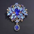 Vintage ornate gold-tone brooch with vibrant blue rhinestones and teardrop crystal - Blue