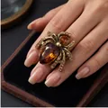 Bague araignée vintage avec cristal ambré et strass champagne présentée sur une main - Style Araignée / Araignée Ambre (Or Antique)
