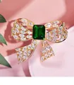 Elegant gold-plated bow brooch with sparkling zircons and a green emerald-cut stone - Brass Bowknot Brooch / Gold