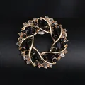 Elegant gold-tone circular brooch featuring black crystals and clear rhinestones - KC Gold Black