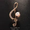 Elegant gold-tone musical note brooch featuring sparkling rhinestones and a pearl accent - Gold/Single Pearl