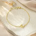 Close-up of gold-plated titanium steel bracelet featuring a delicate M letter charm - Letter M Style / Gold