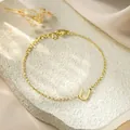 Close-up of a minimalist gold titanium steel bracelet with an initial U pendant. - Letter U Style / Gold