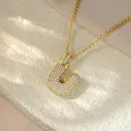High-quality close-up of a gold iced-out bubble letter U pendant necklace with shiny crystals - Letter U / Champagne Gold