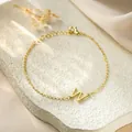 Detailed macro view of a gold titanium steel bracelet featuring a letter W charm - Letter W Style / Gold