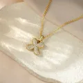 Detailed view of an iced-out gold bubble letter X pendant necklace on a textured stone - Letter X / Champagne Gold