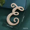 Elegant vintage gold-toned brooch pin featuring letter E inlaid with white pearls - Letter E