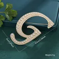 Elegant gold-tone metal brooch shaped like letter G with polished faux pearl inlay - Letter G